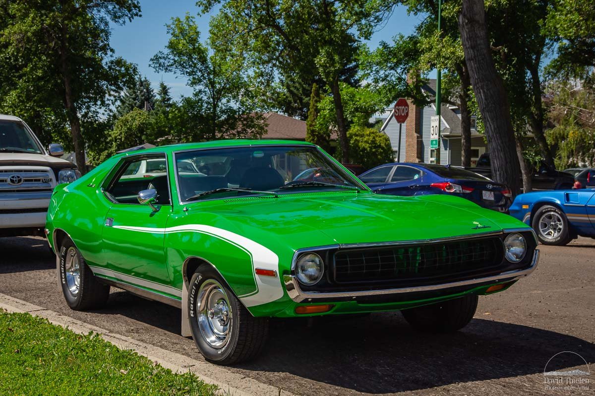 1972-AMC-Javelin-at-Street-Wheelers-Weekend-Lethbridge-July-2025 A 1972 AMC Javelin parked on a street in Lethbridge, Alberta during Street Wheelers Weekend in July 2025. Classic muscle car with bold styling and deep paint color.