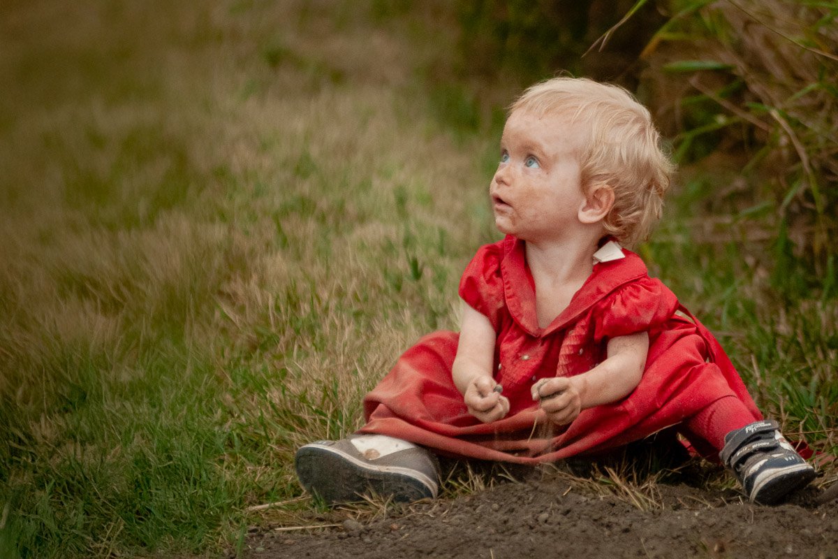 dirty faced little girl sitting in the dirt