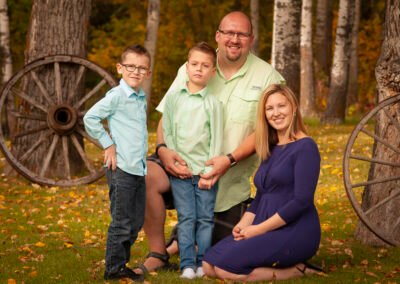 “Adult children pose with their two sons on the grandparents’ acreage during a multi-generational family portrait session, captured by David Thielen Photographic Artistry”
