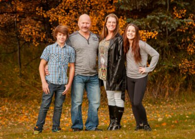 “Entire family poses together outdoors on their private acreage as part of a family session, captured by David Thielen Photographic Artistry”