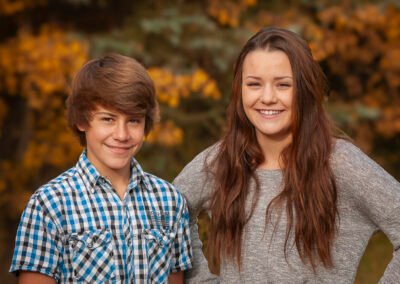 “Brother and sister pose together as part of an extended family portrait session, captured by David Thielen Photographic Artistry”