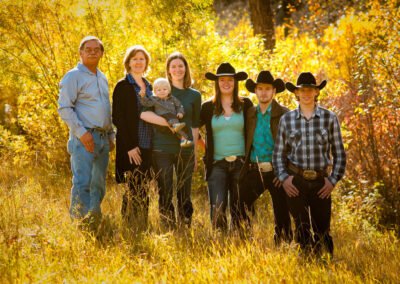 “Extended three-generation family poses outdoors with parents, adult children, a daughter holding her toddler, and a son with his wife, captured by David Thielen Photographic Artistry”