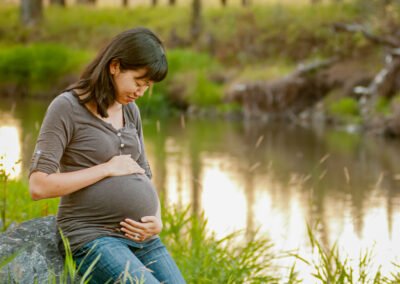 “Mother cradles her baby bump in soft, rimmed lighting, captured in a tender maternity portrait by David Thielen Photographic Artistry”