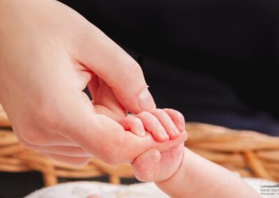 “Close-up of a parent holding their newborn’s hand, capturing the tiny fingers and the wonder of early parenthood, photographed by David Thielen Photographic Artistry”